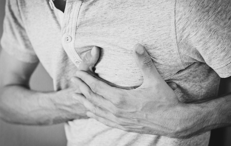 Mężczyzna trzymający się za klatkę piersiową z powodu bólu